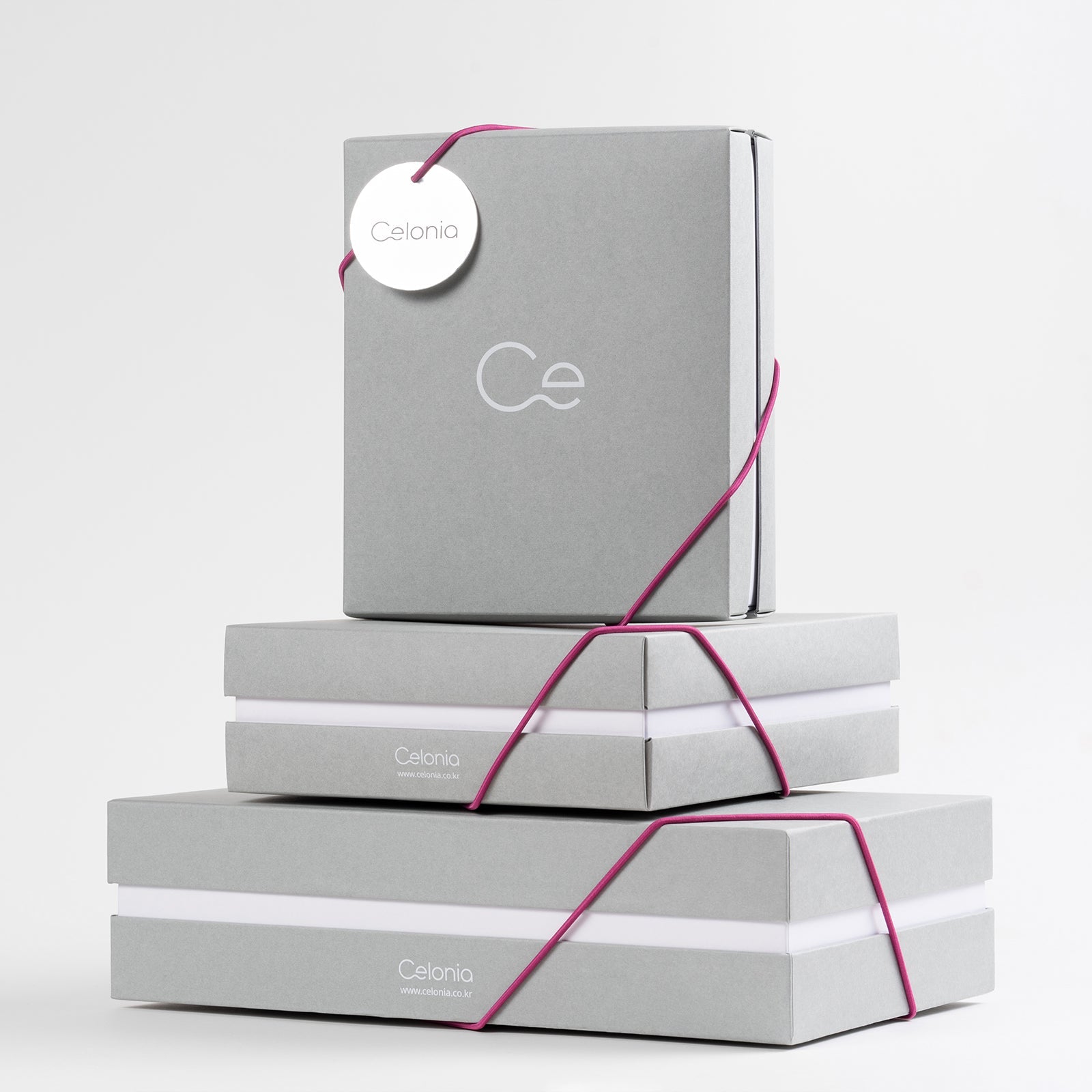 Elegant Celonia gift boxes in minimalist grey packaging with pink ribbon accents for luxury skincare presentation
