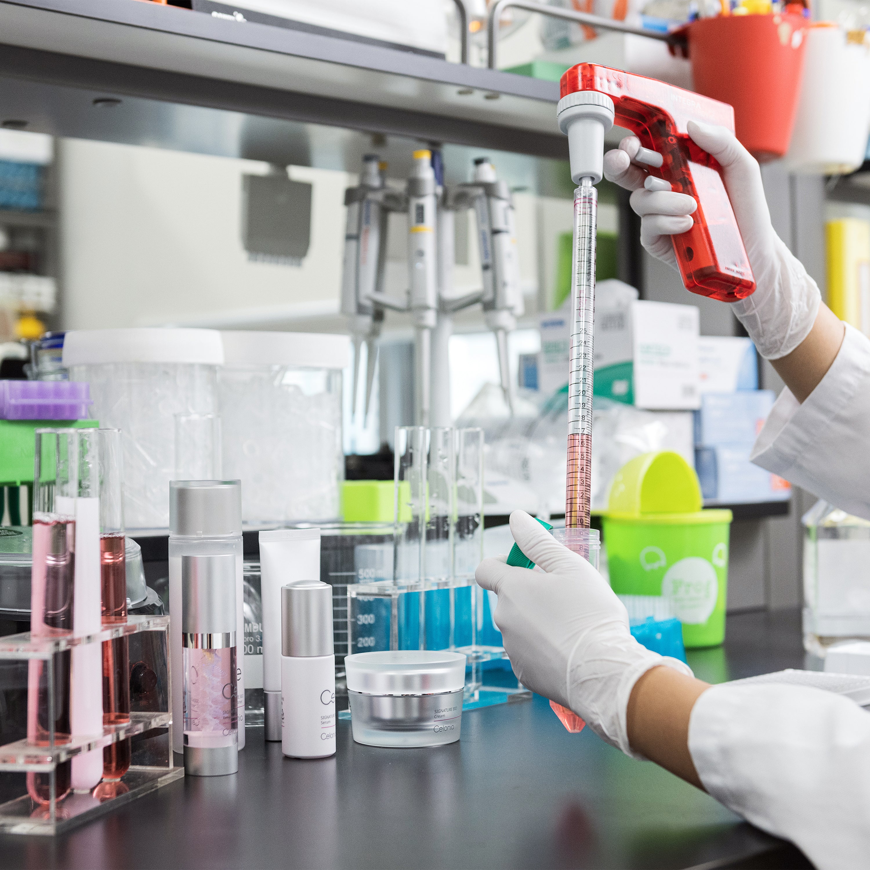 Person in a lab setting using a pipette with laboratory equipment in the background
