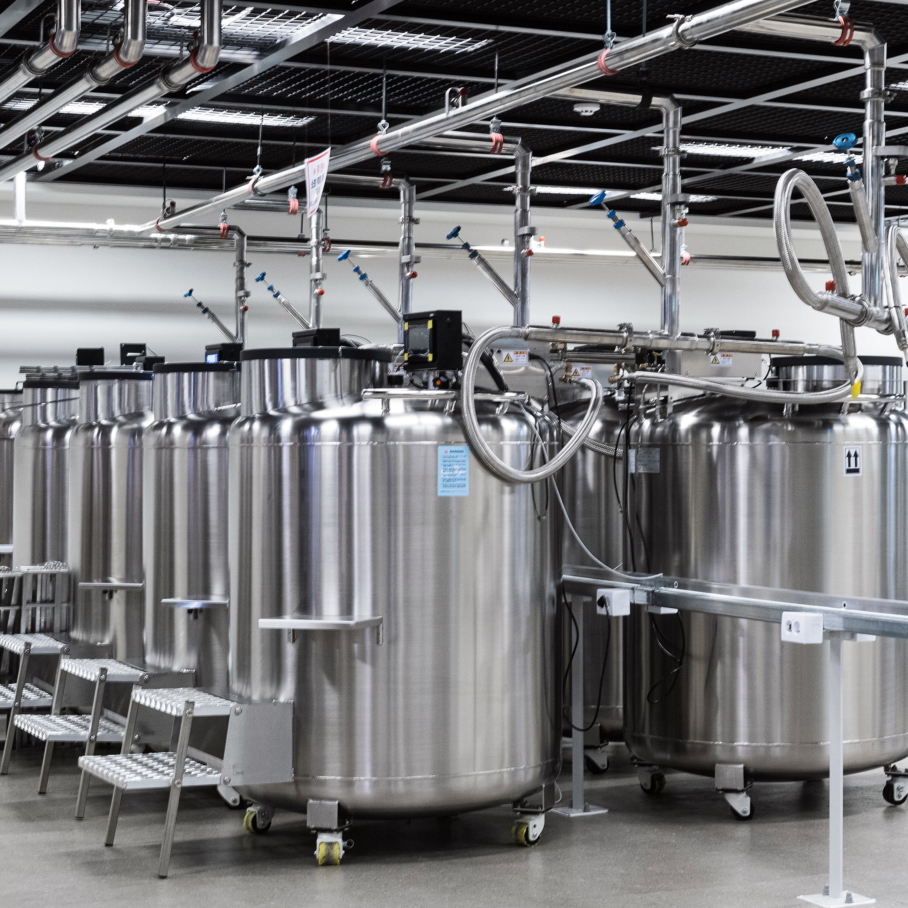 Row of large metallic tanks in a factory setting