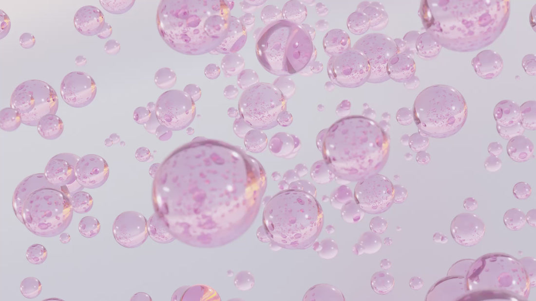 Floating pink serum bubbles in a bright background, representing hydration and active skincare ingredients.