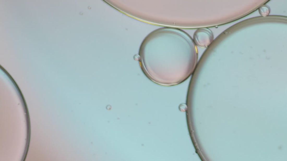 Close-up of transparent serum bubbles with soft pastel reflections, symbolizing hydration and lightweight skincare texture