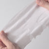 Hands holding a soft, flexible sheet mask demonstrating its stretchable and skin-hugging texture for better facial coverage.